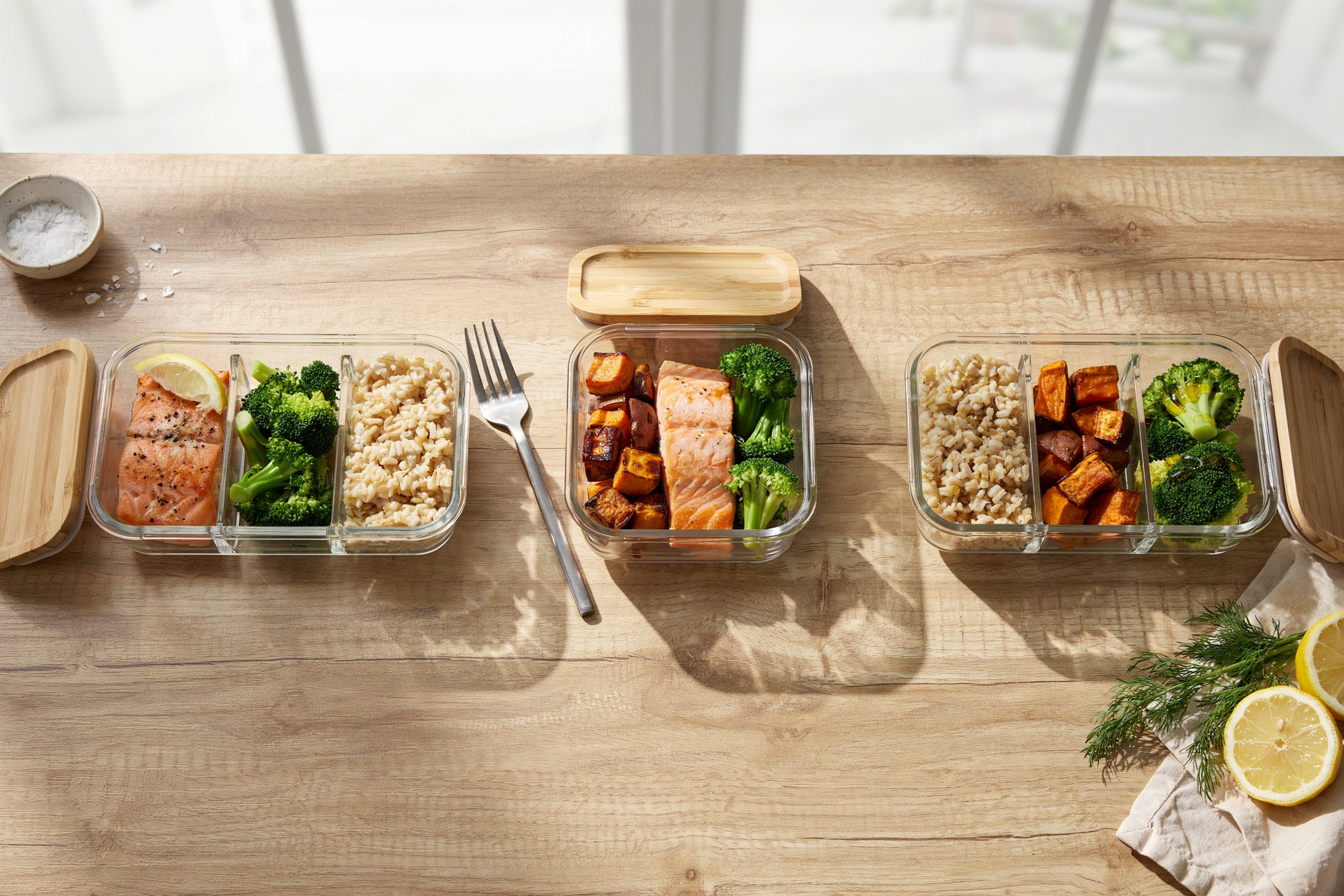 Weekly meal-prep containers with balanced portions of salmon, broccoli, rice and sweet potato